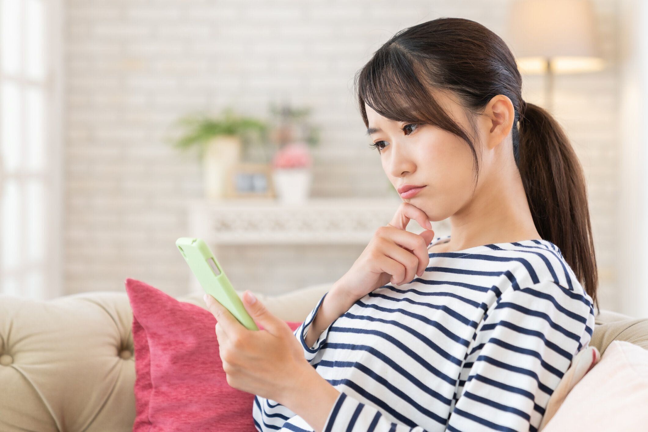 スマートフォンを使用して魅力的なアジアの女性、考える、