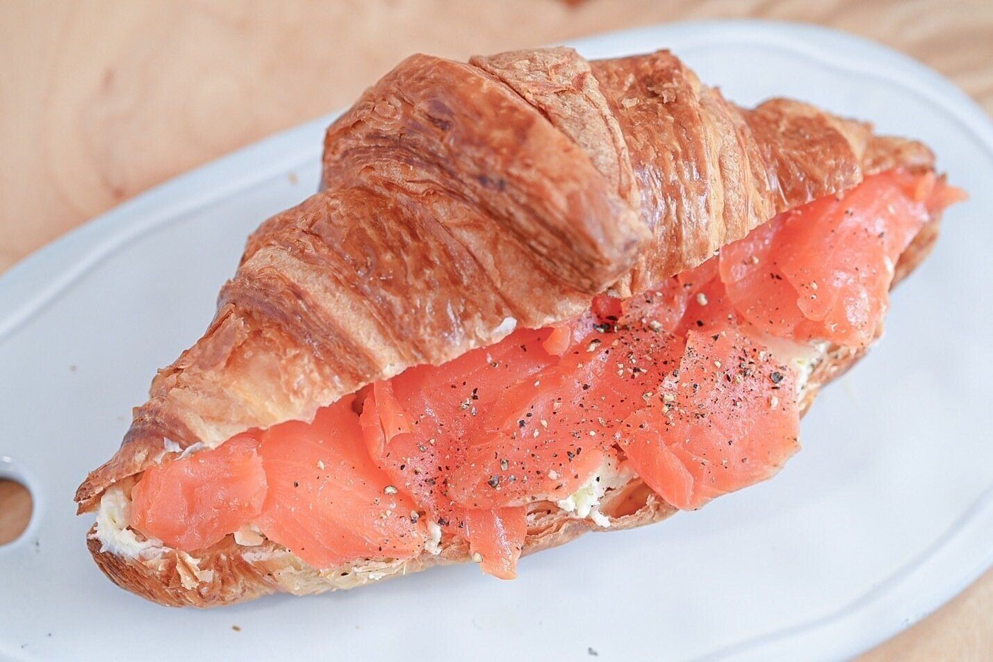 皿に盛られたスモークサーモンとクリームチーズのクロワッサンサンド