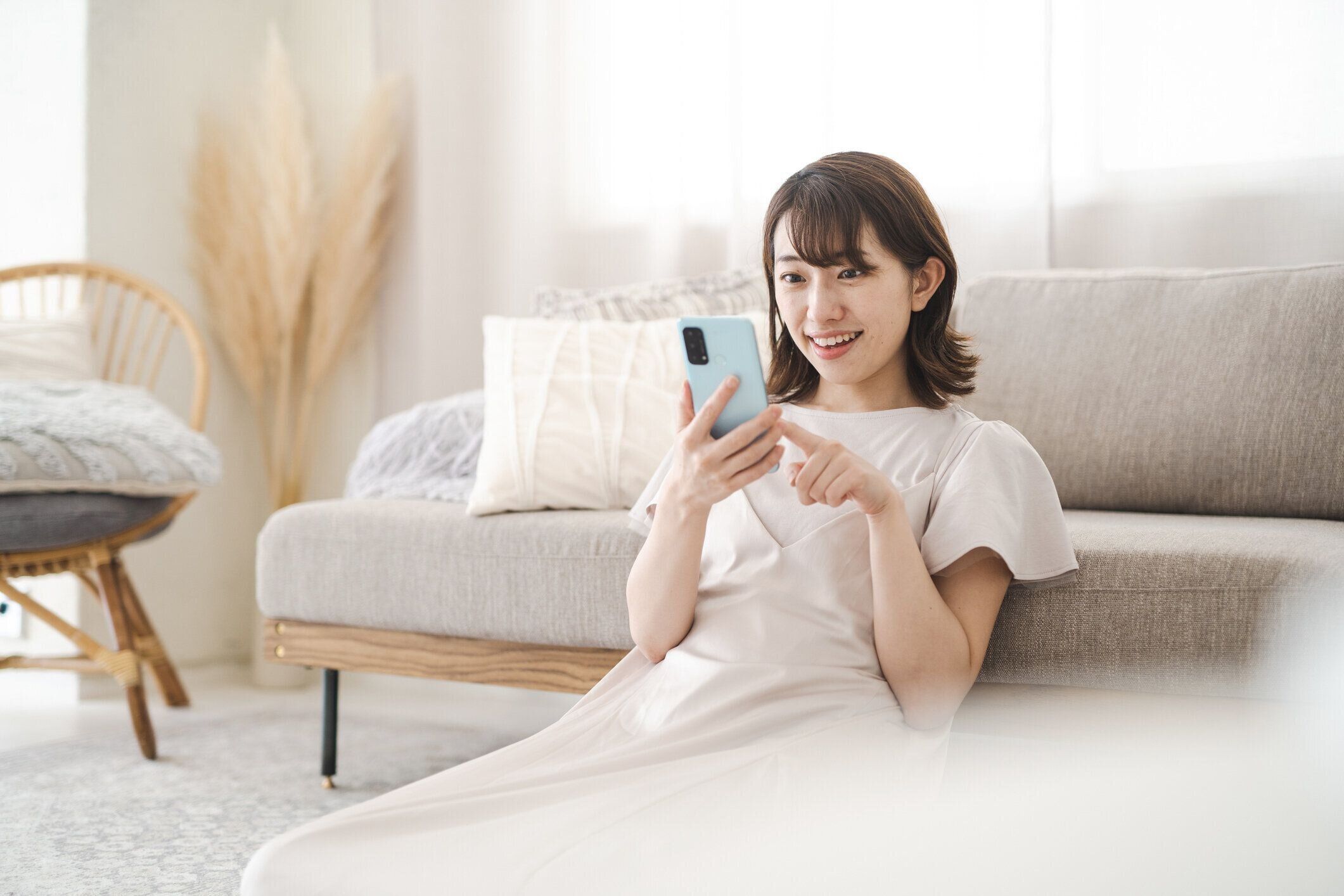 部屋でスマホを操作する日本人女性