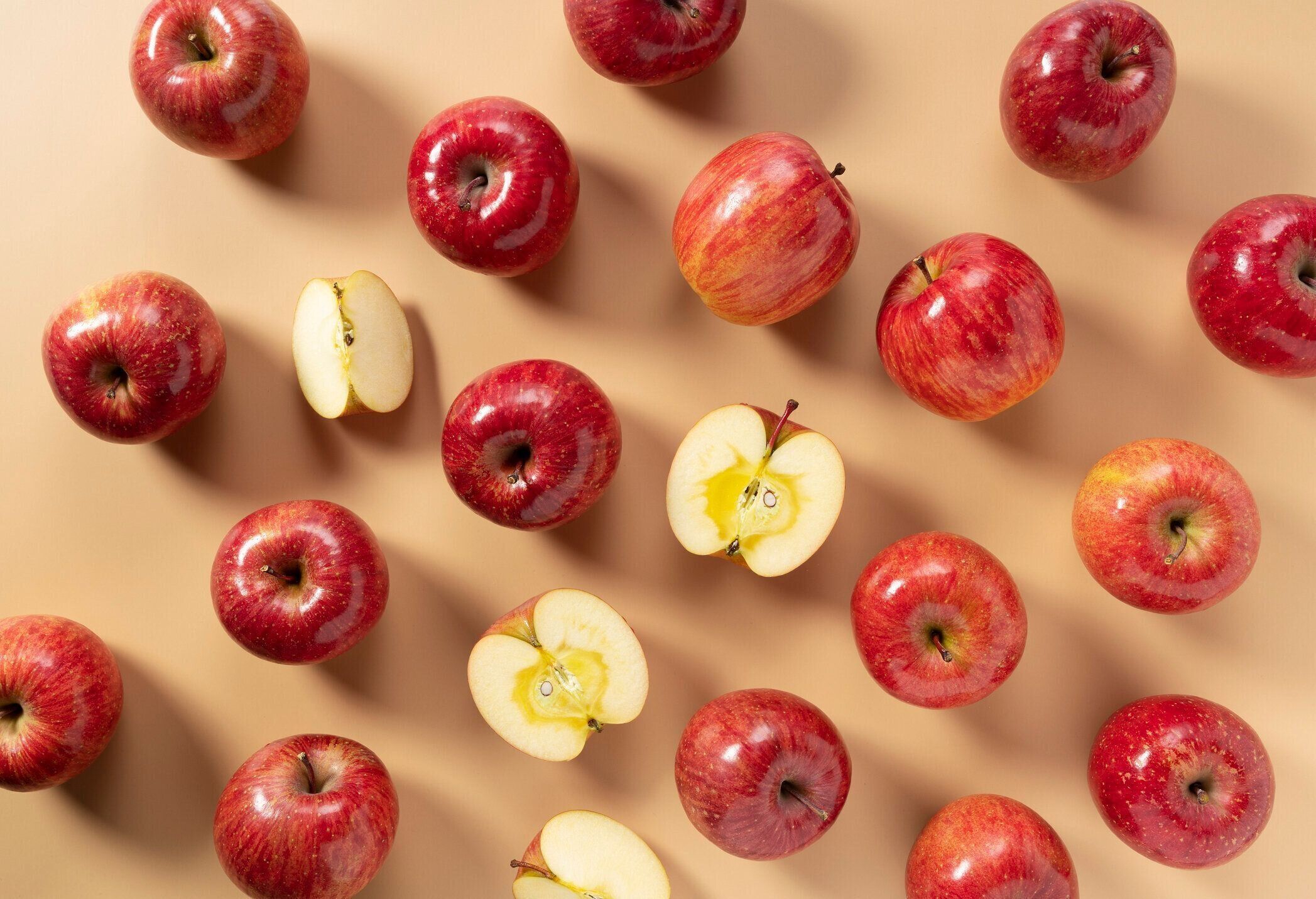 ベージュの背景に置かれたリンゴの多くは、半分または4分の1にカットされます。