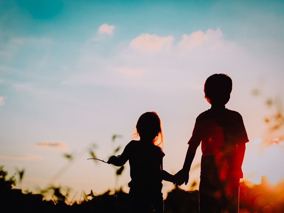 夕暮れ時の手を保持している小さな男の子と女の子シルエット