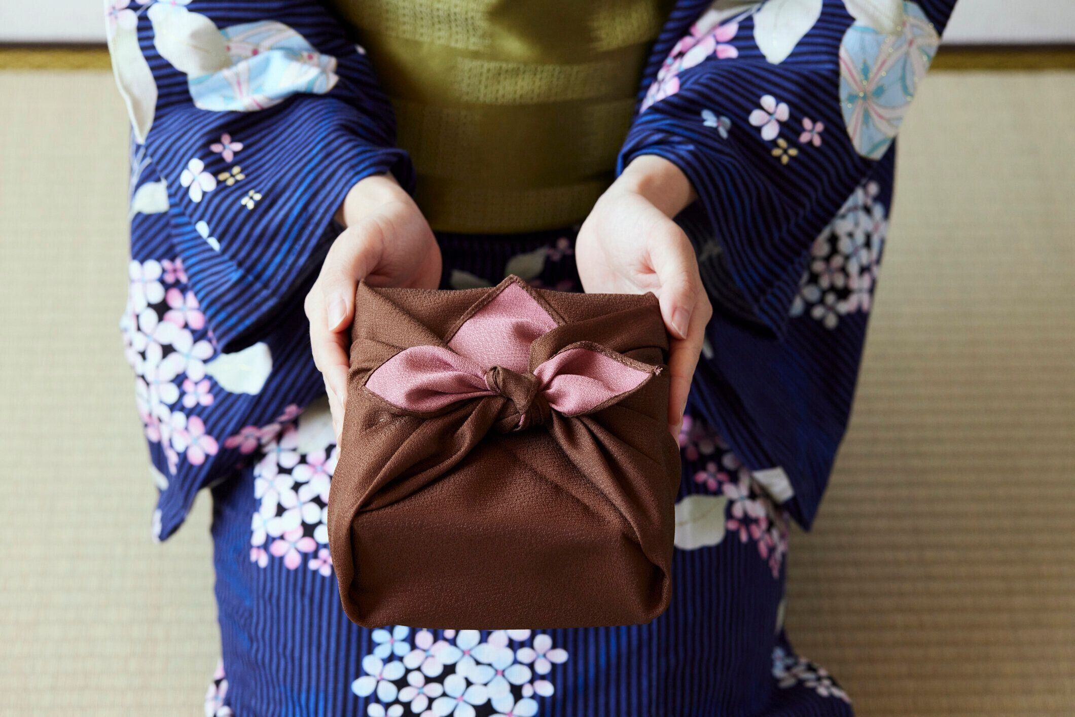 贈り物を示す日本の服を着た女性の手