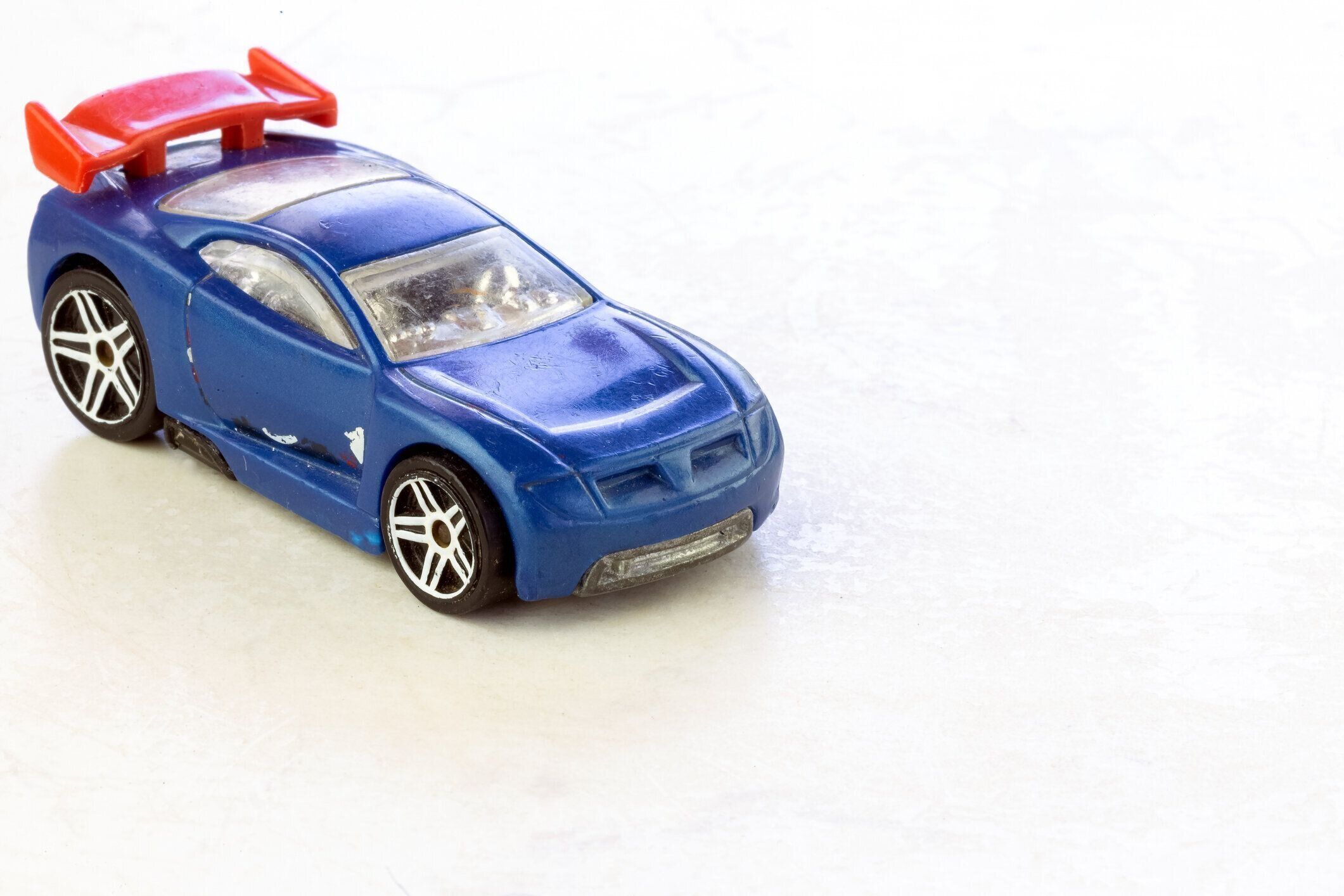 白い大理石の背景に隔離された古くてみすぼらしい青い子供のおもちゃのベビーカー。