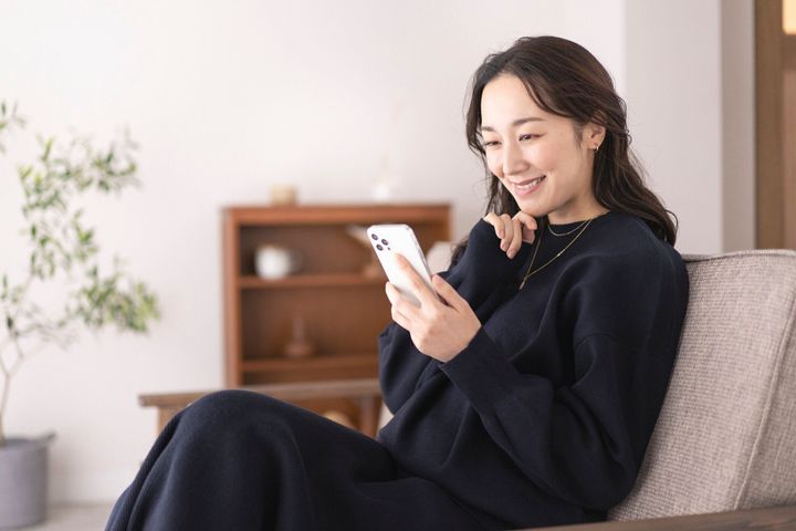 日本の女性の生活シーン、彼女は自分の携帯電話を見ています。