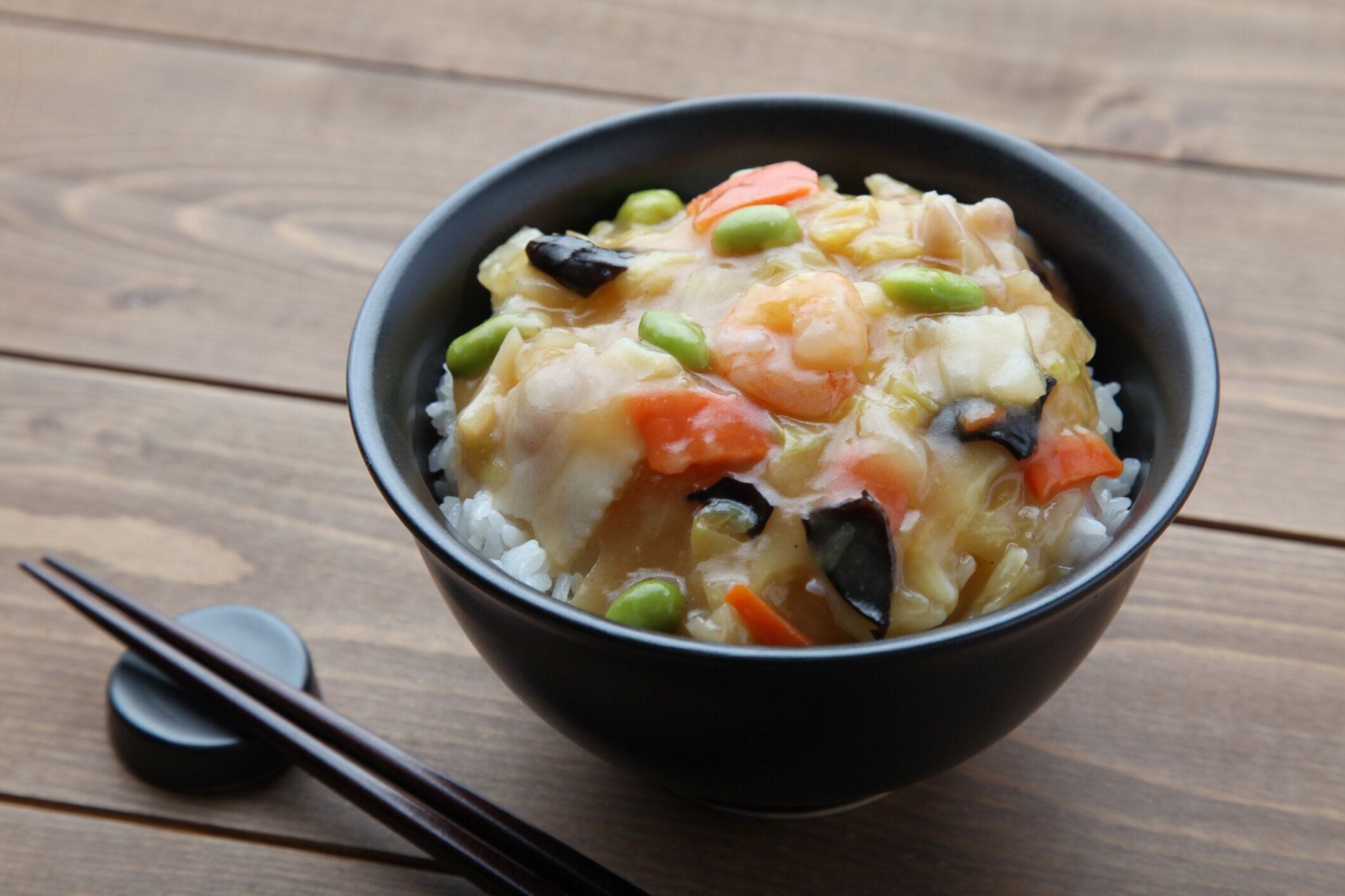 テーブルの上に切り箸を置いた米丼中国風野菜肉シーフード