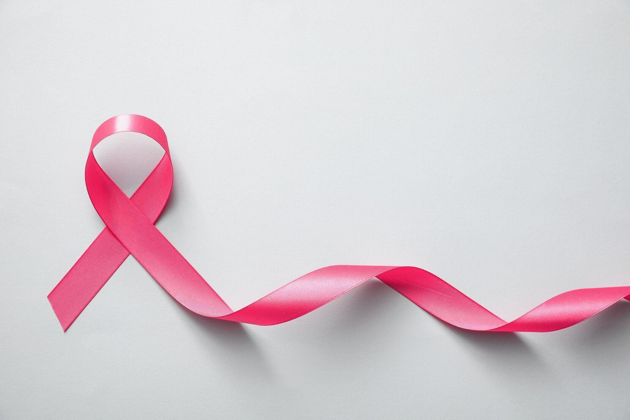 ライトグレーの背景にピンクリボン、トップビュー。乳がん啓発コンセプト