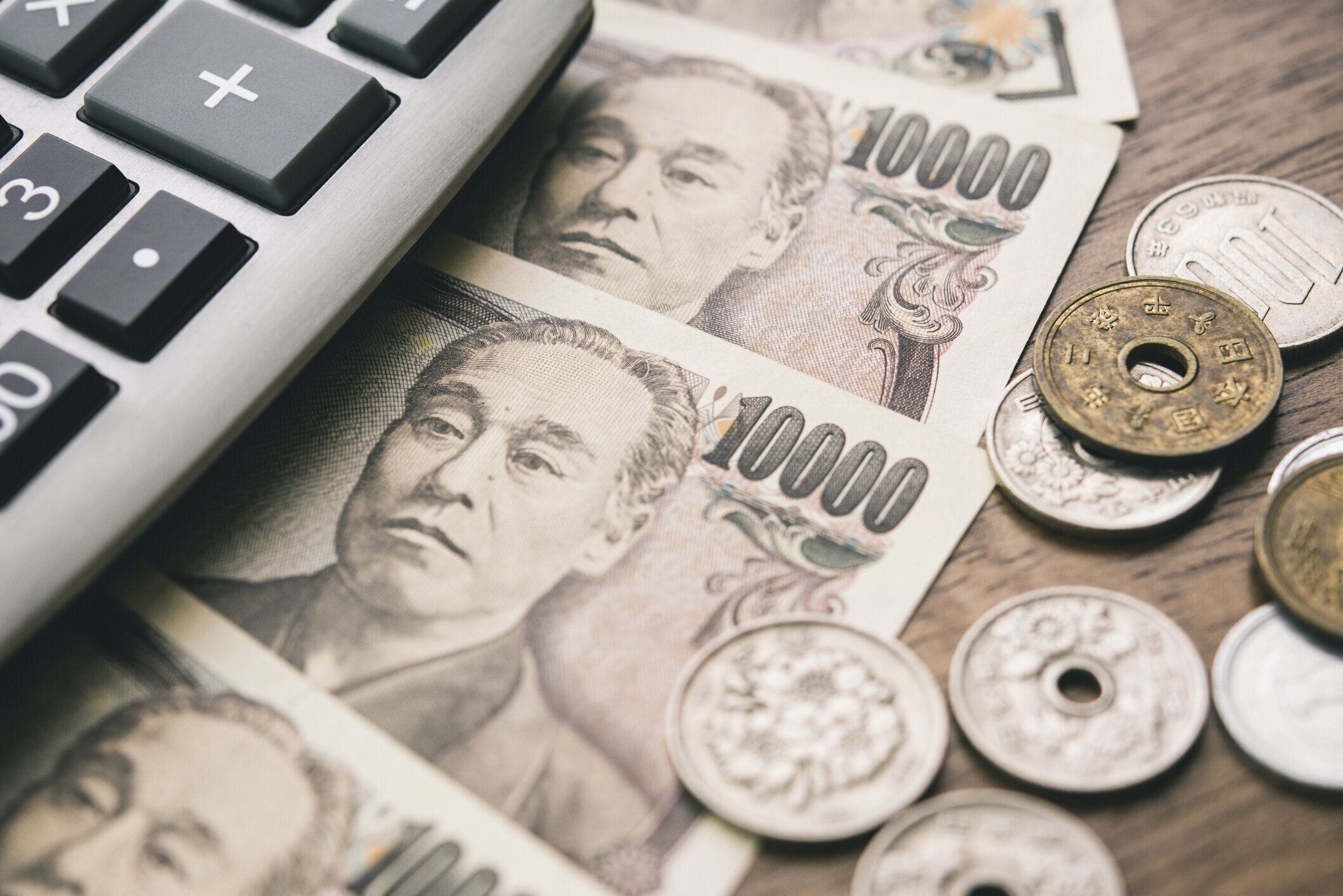 テーブルの上に電卓付き日本円紙幣と硬貨