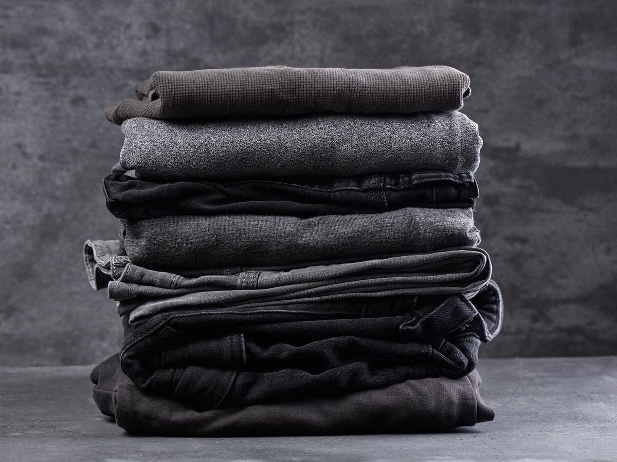 黒い灰色の背景クローズアップで隔離されたきれいに折りたたまれた暗い服のスタック
