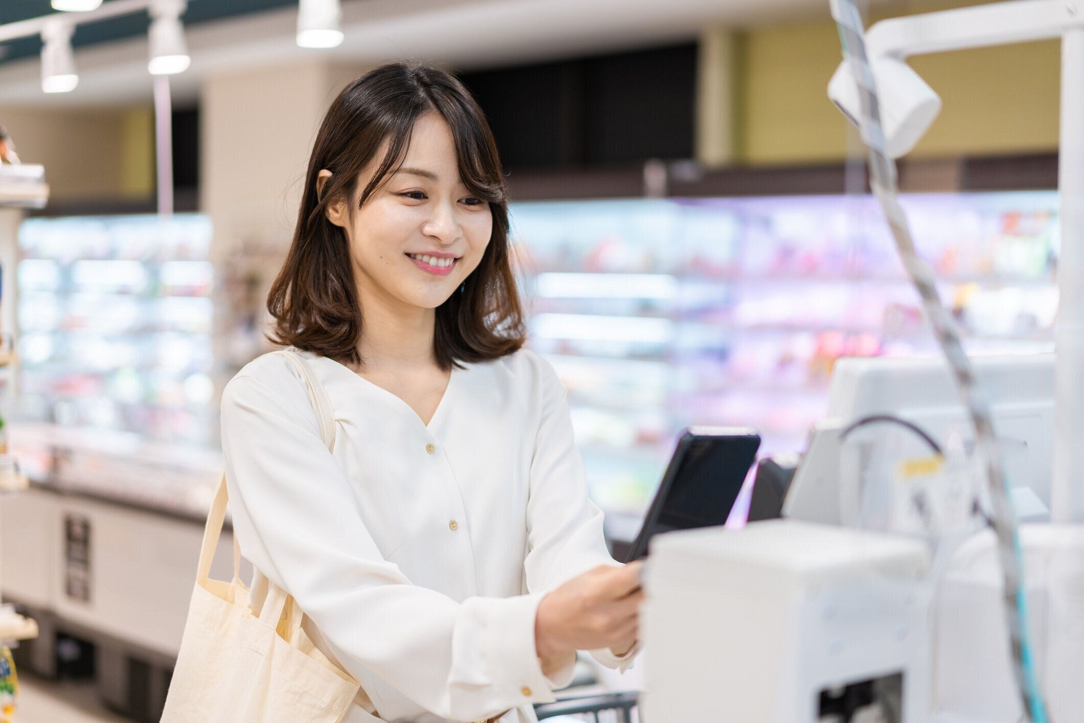 セルフチェックアウトと電子マネーの支払いを使用して若い女性