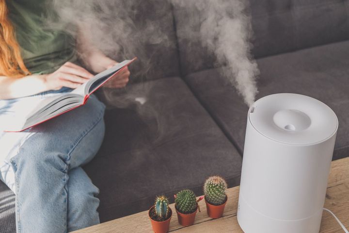 ソファで読む女性の近くのテーブルの上の自宅で家庭の加湿器