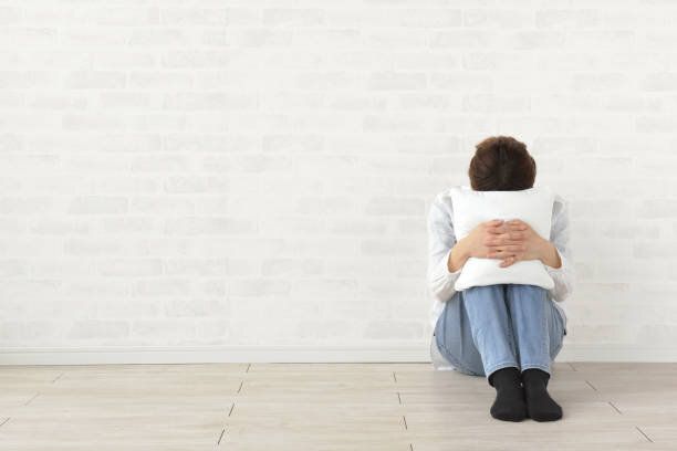 リビングルームのクッションに顔を埋めるうつ病の女性