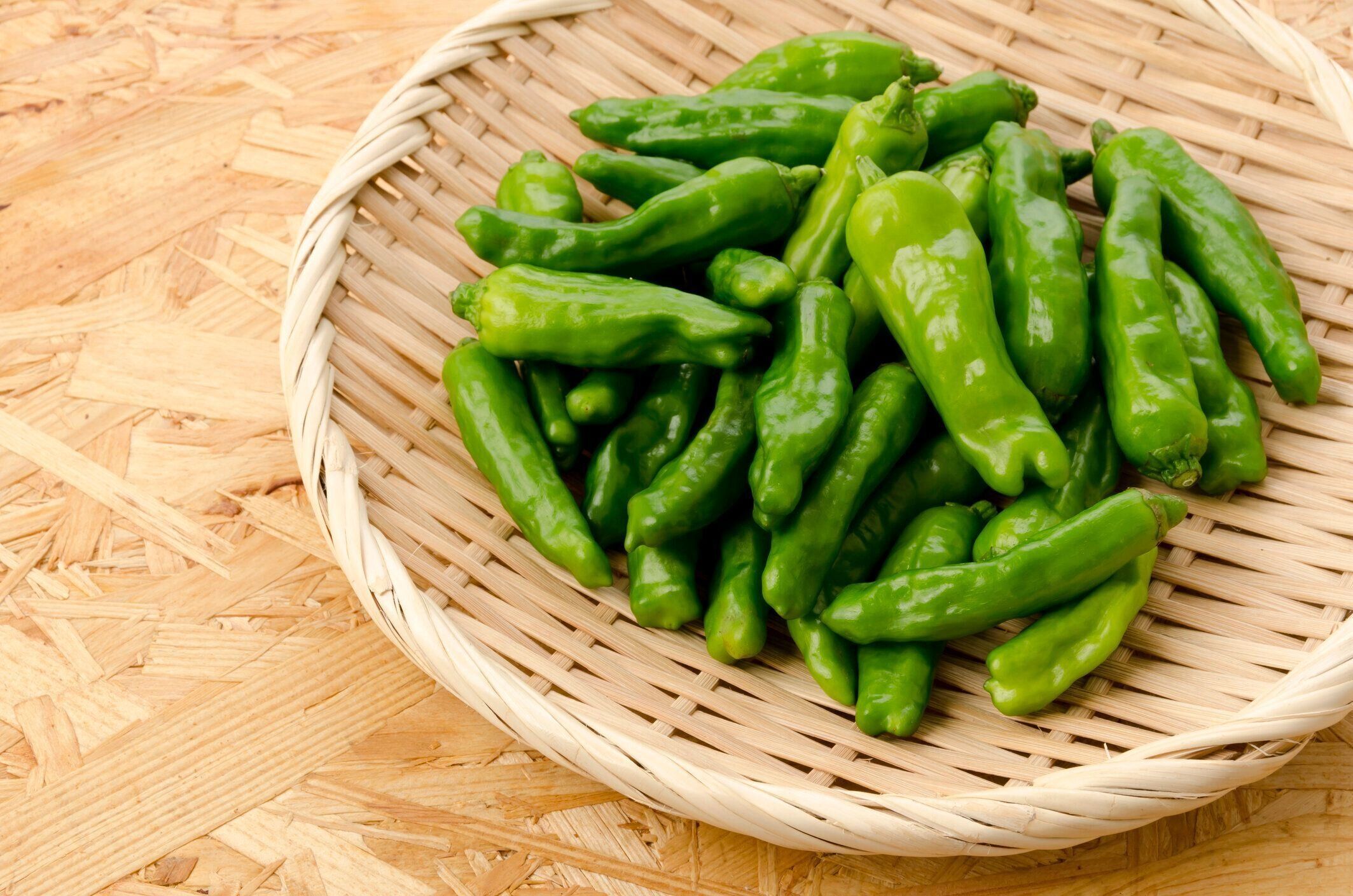 合板ボードの背景に竹のふるいに獅子とピーマン