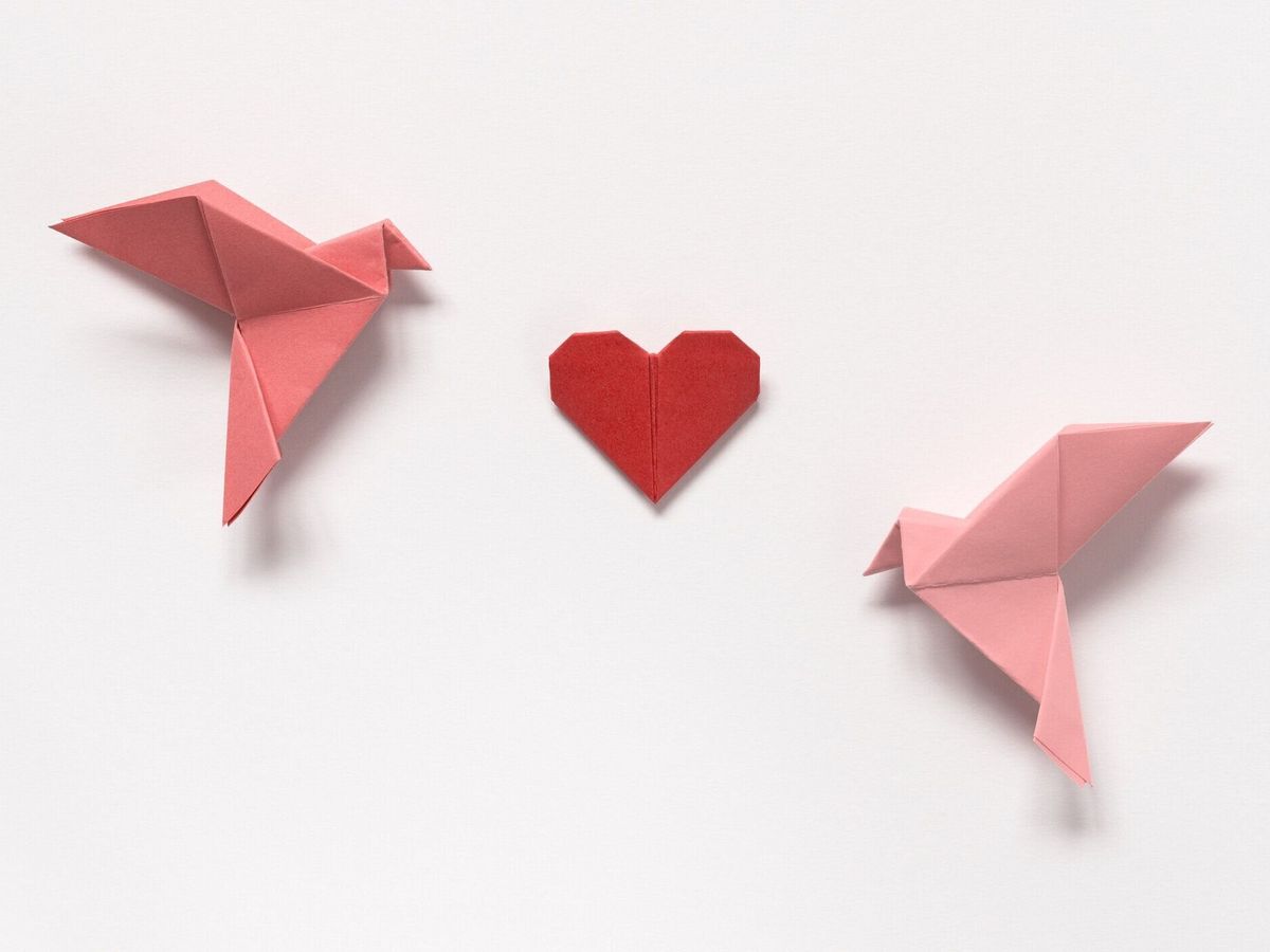 ピンクの鳥や白い背景の折り紙の赤いハート。バレンタインデーのためのギフトカード。