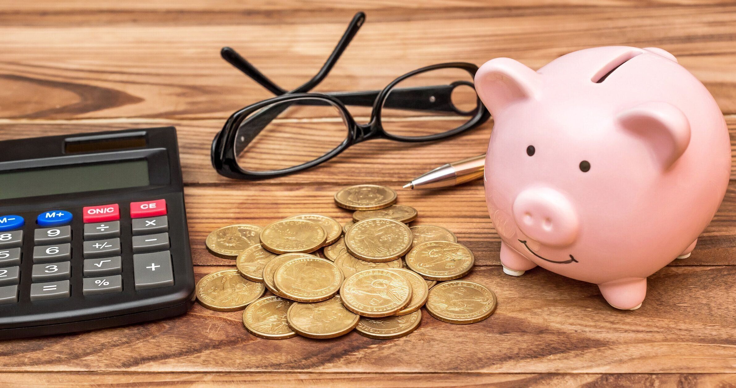 貯金箱のコインと木製のテーブル上の電卓。金融の概念。
