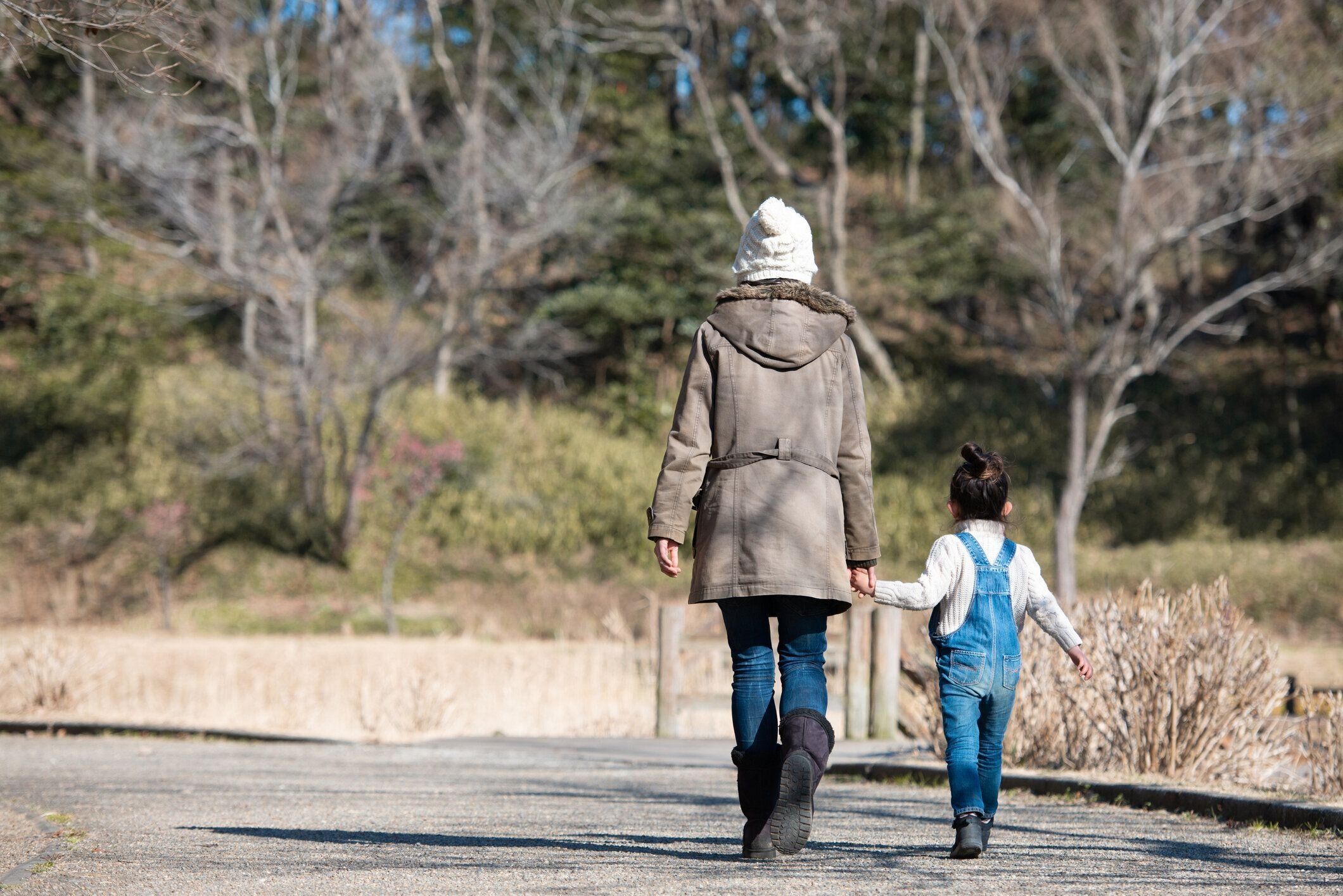 冬の公園で手をつないで歩く親子