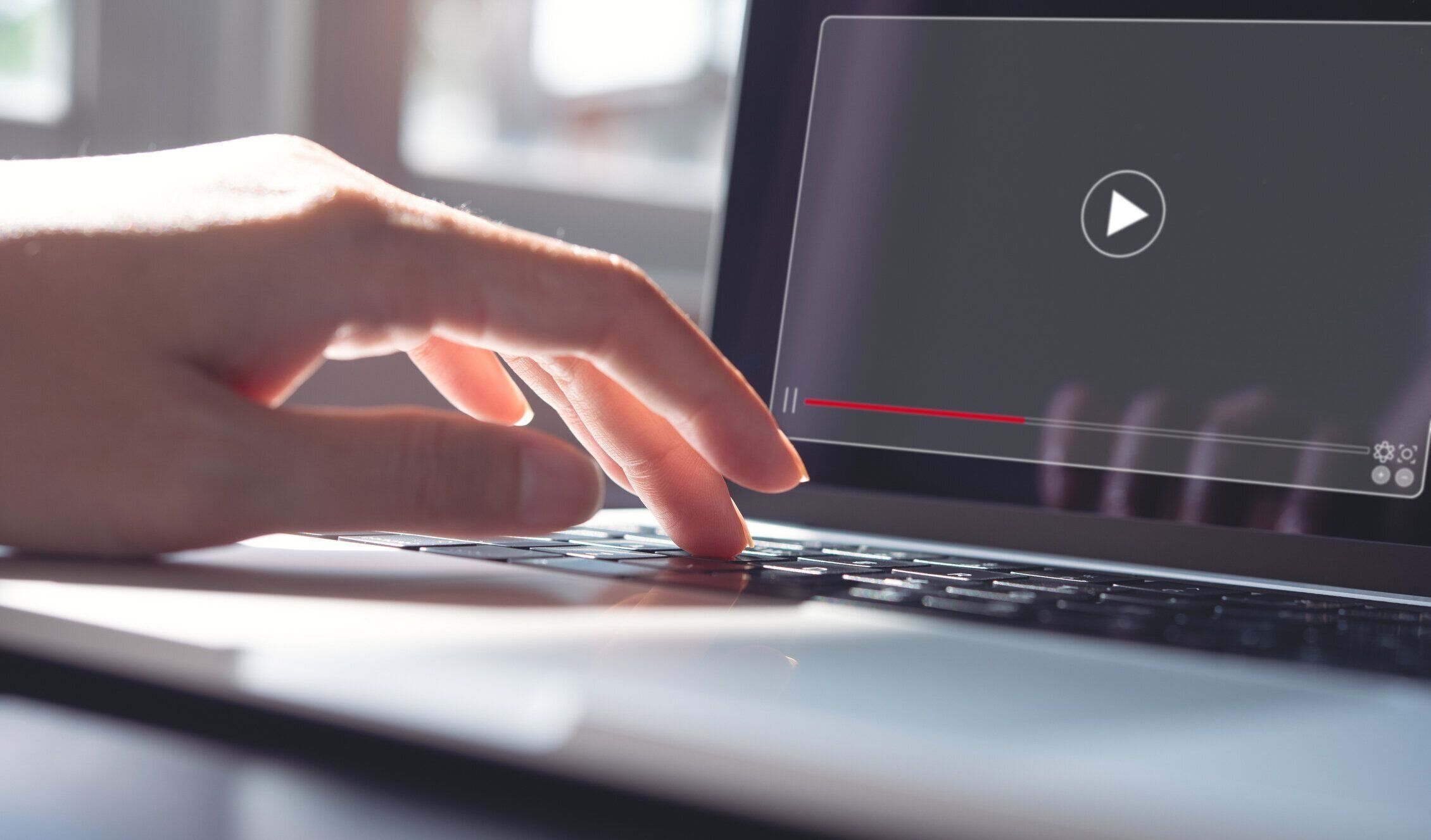 ラップトップコンピュータで作業し、ビデオプレーヤーを見ている女性