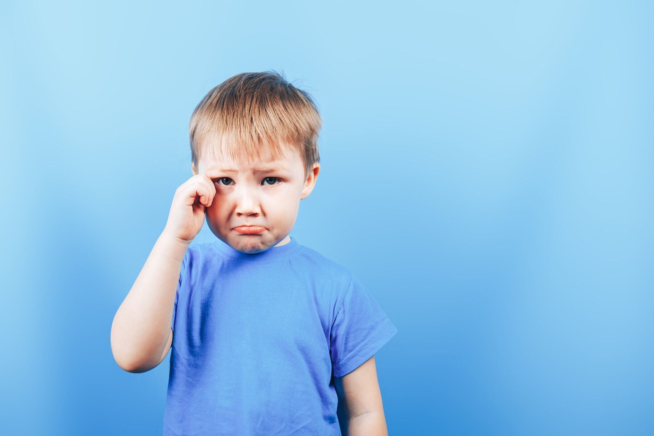 青い背景で泣いている悲しい少年を動揺