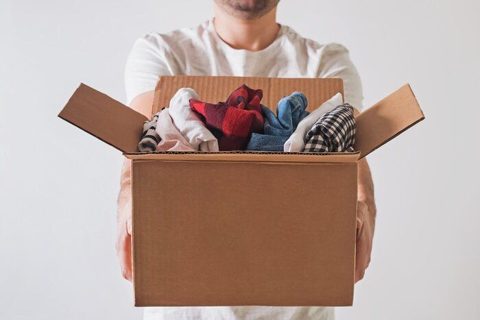 服だらけの段ボール箱を持っている認識できない男。