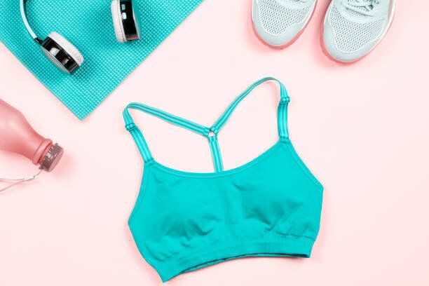 女性のフィットネス服やアクセサリーフラットは、ピンク、コピースペースに横たわっていました。スポーツブラジャー、ヨガレギンス、ヘッドフォン、ヨガマットを持つ女性のためのスポ�