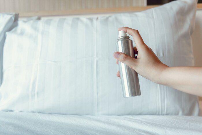 女性の手は、寝室、不快な臭いやアロマセラピーの概念上の枕に空気フレッシュナーを噴霧されています