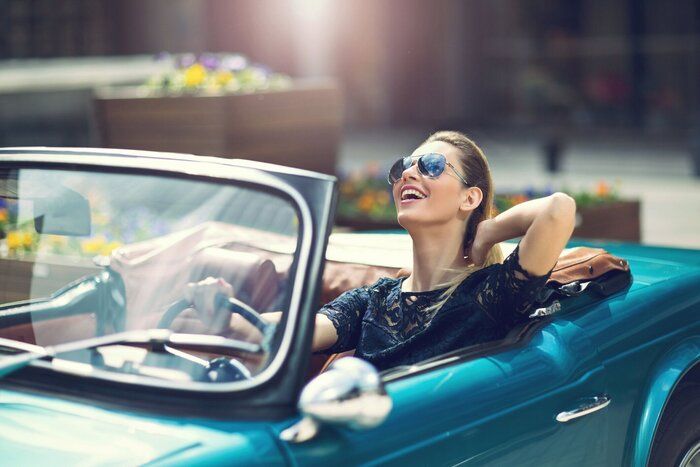 高級レトロな車に座っているサングラスの女性ファッションモデル