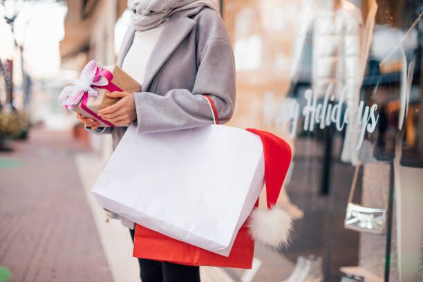 クリスマスプレゼントやショッピングバッグを持つ女の子のクロップド画像、テンプレート、モックアップ白いバッグ、クリスマスショッピングコンセプト