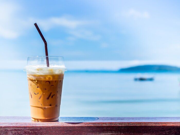 海背景に木の棒にミルクとアイスティー