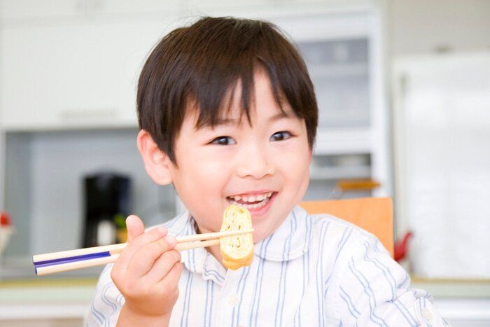 男の子は、お箸で卵を揚げています。