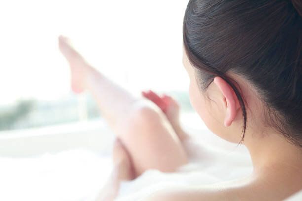 女性がお風呂で足をマッサージします。