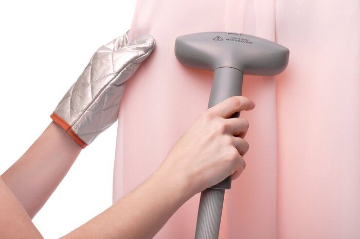 手動蒸し器を使用して保護手袋を着た女の子は、服、白い孤立した背景、クローズアップを滑らかにします。