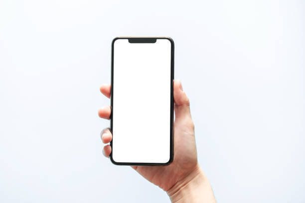 スマートフォンのモックアップ。黒い電話の白い画面を持つ手。白い背景に隔離されています。携帯電話フレームレスデザインコンセプト。