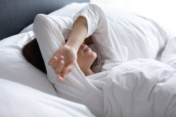 不眠症に苦しむ眠れない若い女性、手で目を覆う