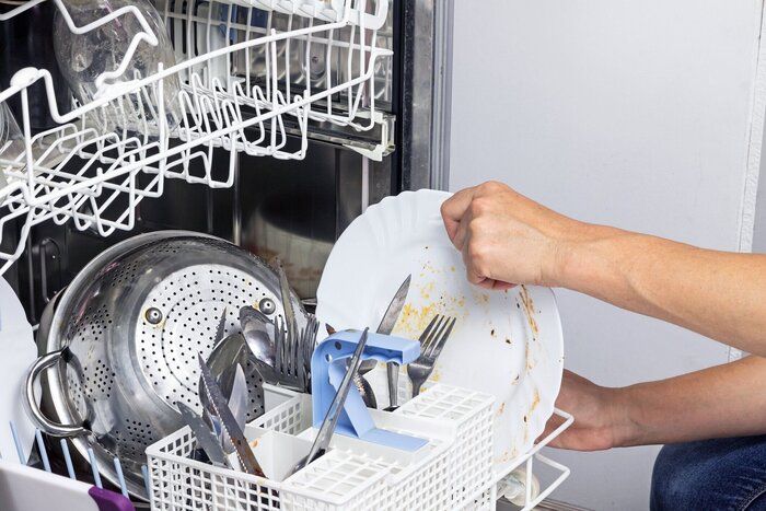 主婦は、食器洗い機に汚れた皿を置く