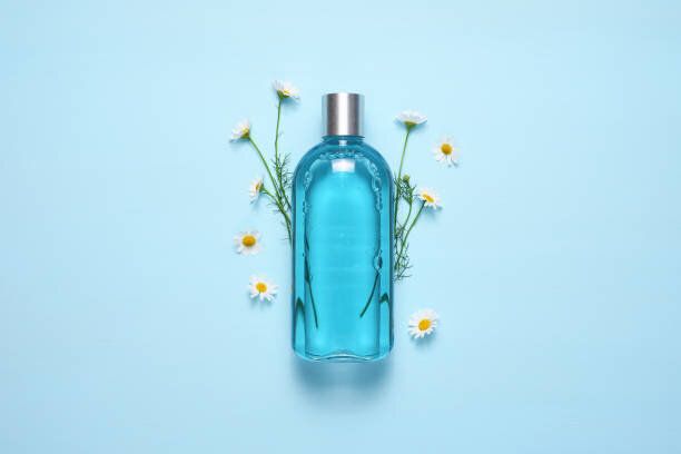 青いテーブルトップビューの化粧品ボトルとカモミールの花
